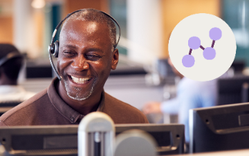 Smiling call center agent wearing headset at desk with analytics icon