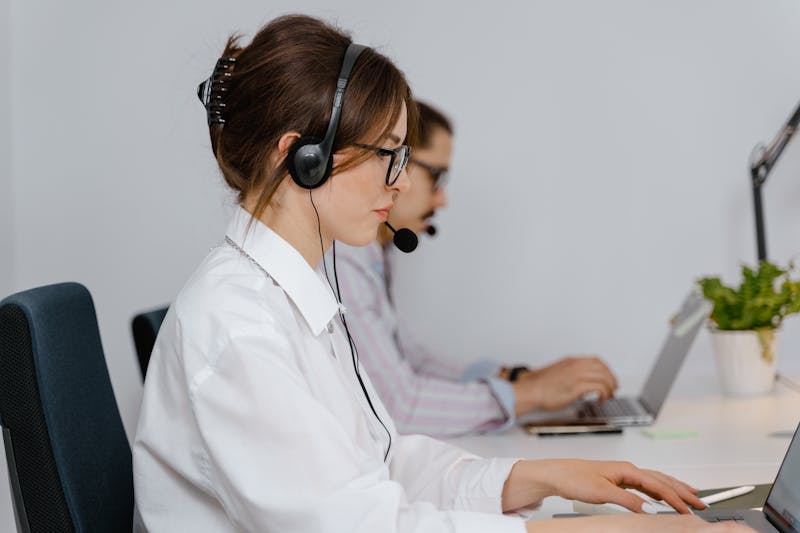Dos agentes de un centro de llamadas trabajan en sus mesas con auriculares.
