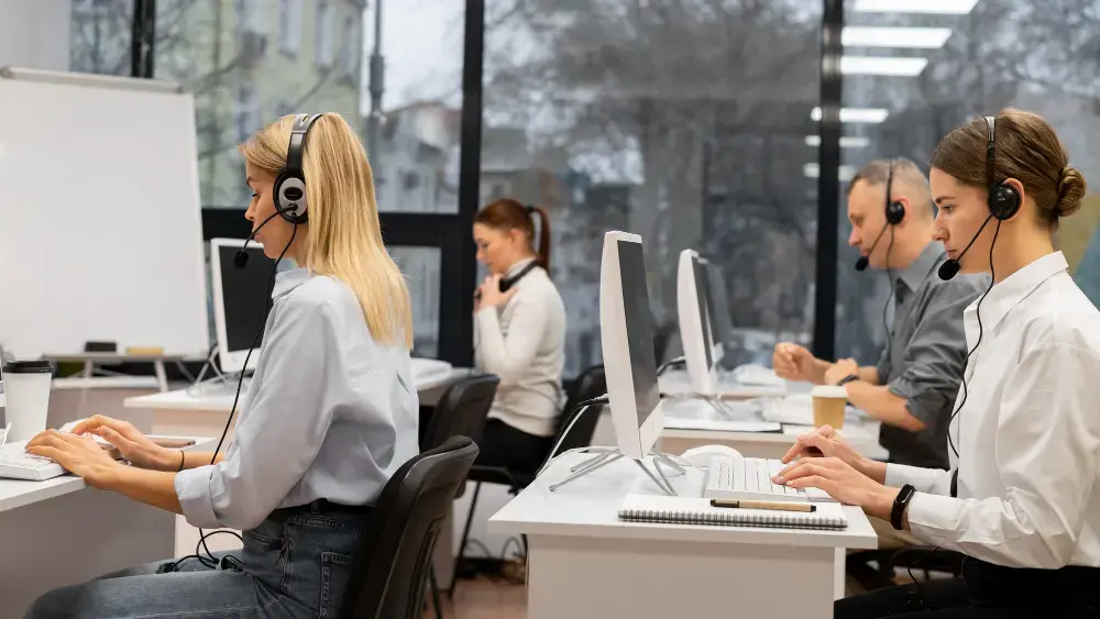 Agentes del centro de llamadas que utilizan auriculares y ordenadores en una oficina moderna, demostrando habilidades clave de atención al cliente y comunicación.